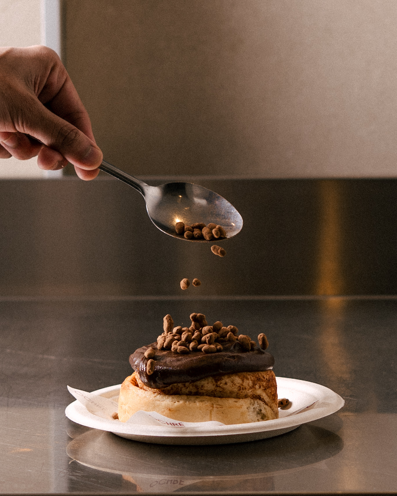 Chocolate roll being finished with cocoa pearls